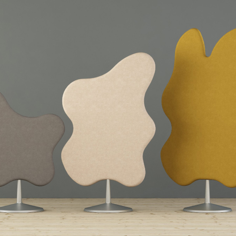 Tre abstrakta, oregelbundet formade rumsavdelare står på ett ljust trägolv mot en grå bakgrund. Avdelare är i grå, beige och senapsgula färger, var och en stödd av en central metallbas.