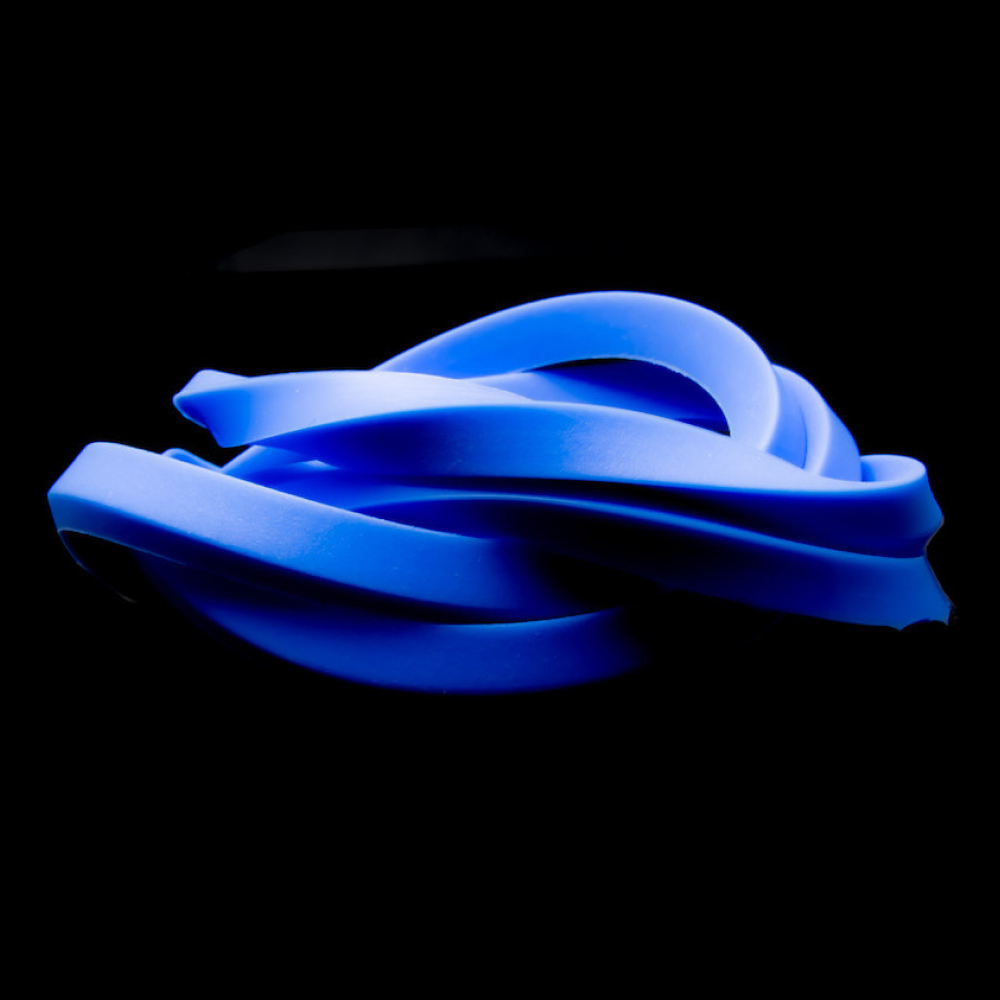 En tvinnad bunt blå gummiband är inställd mot en svart bakgrund. Banden överlappar varandra och flätas samman, vilket skapar ett trassligt utseende. Den blå nyansen är livfull och framträder tydligt mot den mörka bakgrunden.