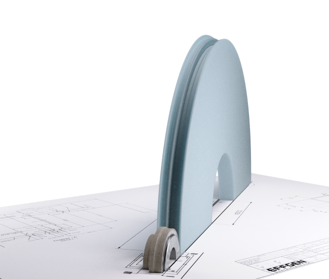 En blå arkitektonisk modell står ovanpå en detaljerad teknisk ritning. Ett litet föremål med hjul är fäst på modellens bas, placerat på en platt, tryckt pappersyta.